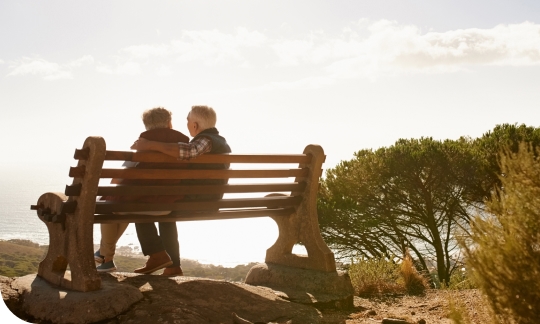 A retired couple sit enjoying the sunset, free from financial stress with the help of a reverse mortgage.